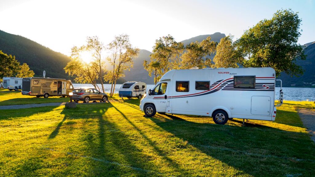 Several motorhomes and a caravan on grass by a lake