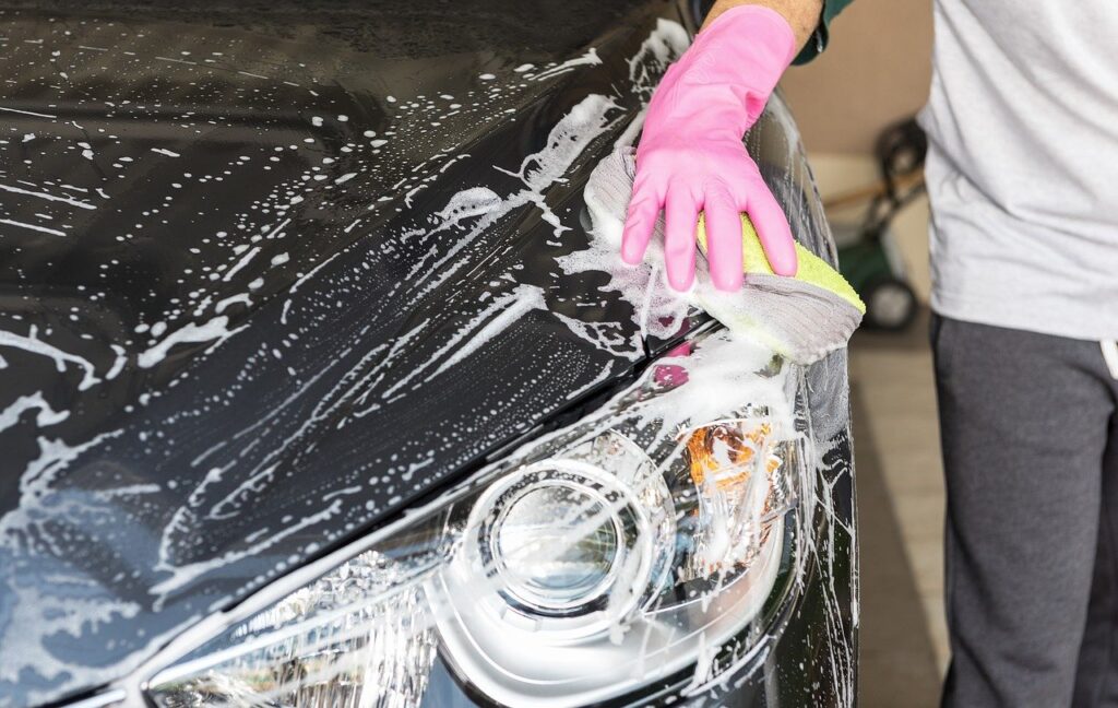A person washes a motorhome with a cloth and detergent