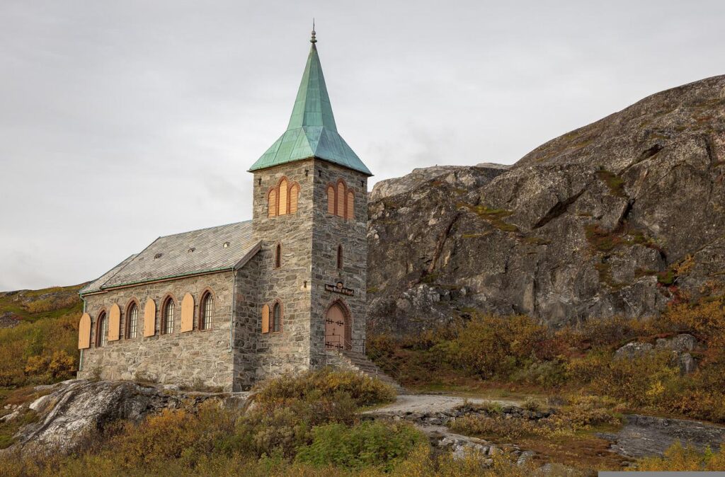 A small stone church with mountains in the background