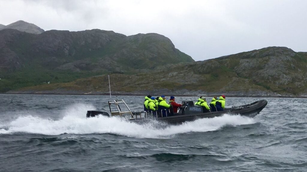 Rib boat at full speed on the sea, with mountains in the background